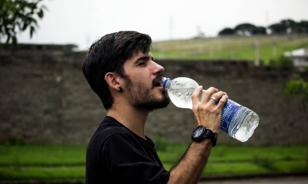 a man drinking from plastic bottled water
